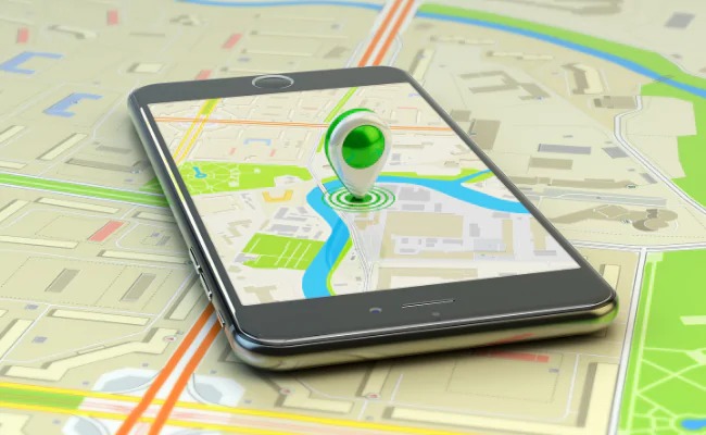 Imagem mostra um celular sobre uma mesa e um mapa exibindo um aplicativo de rastreamento com uma posição em destaque